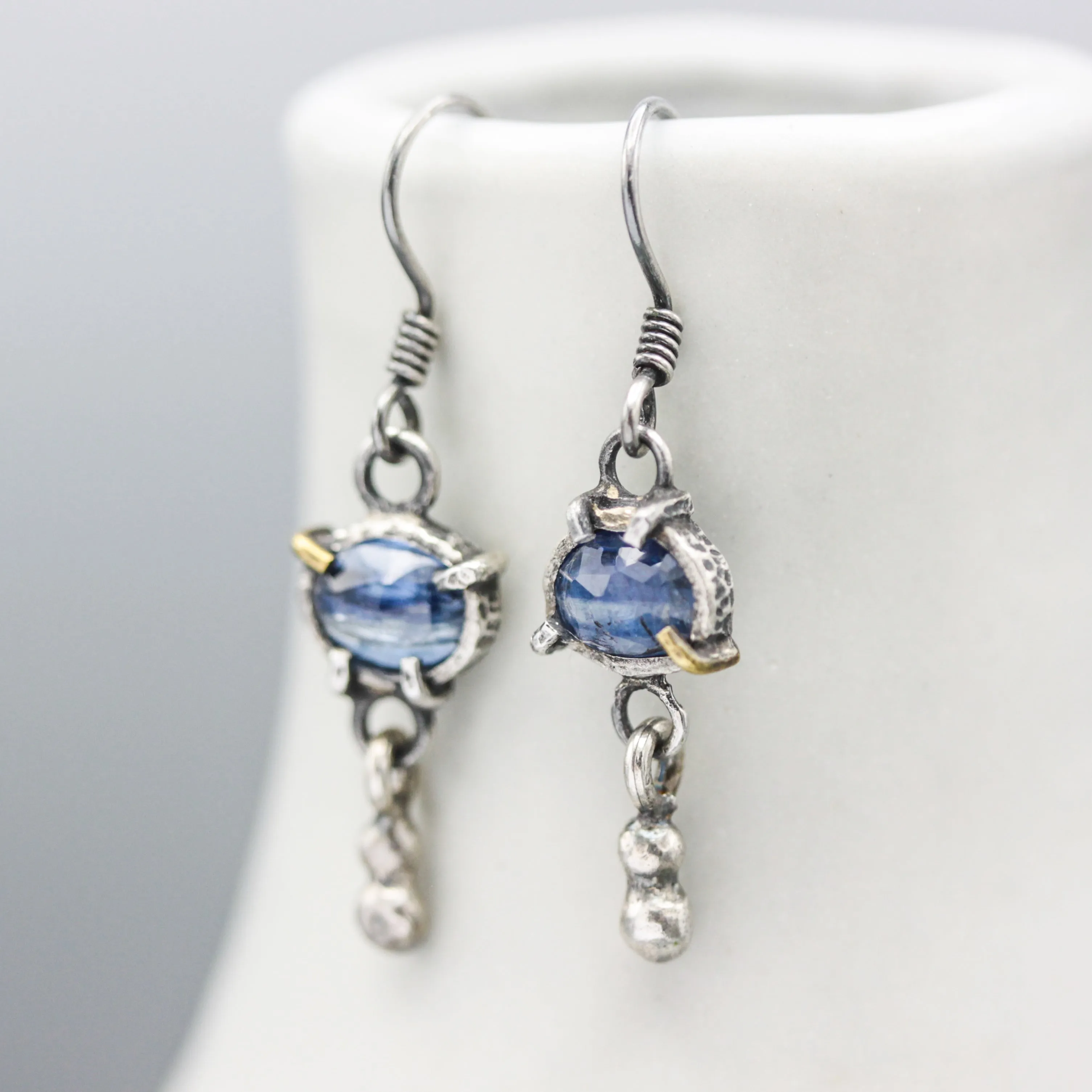 Oval blue kyanite earrings in silver bezel and prongs setting with silver beads on oxidized sterling silver hooks style