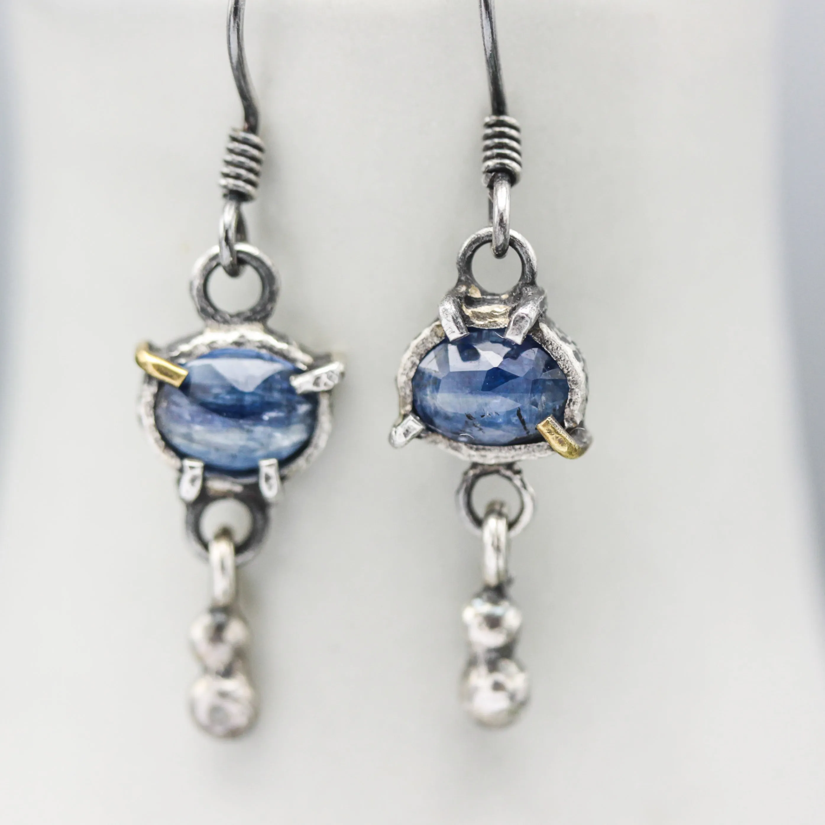 Oval blue kyanite earrings in silver bezel and prongs setting with silver beads on oxidized sterling silver hooks style